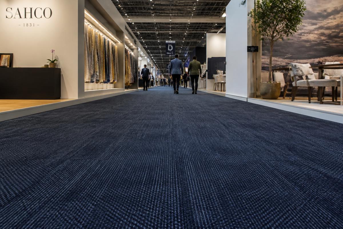 Low-angle view of a long trade show aisle with navy natural-fiber carpet